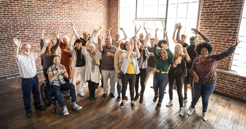 a diverse group of people with arms raised in celebration